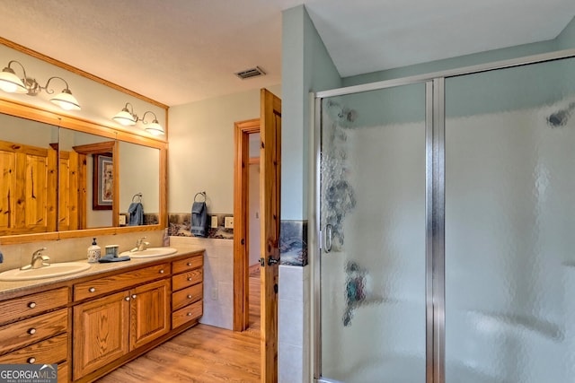 bathroom with a shower with door, hardwood / wood-style floors, and vanity