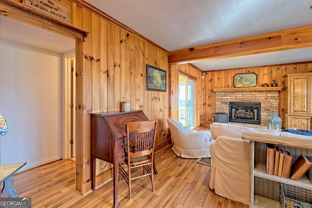 living room featuring wood walls, light hardwood / wood-style floors, and a stone fireplace