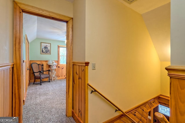 stairs with carpet floors, wooden walls, vaulted ceiling, and ceiling fan