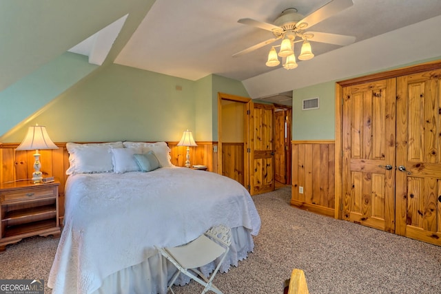 carpeted bedroom featuring ceiling fan, wooden walls, and vaulted ceiling