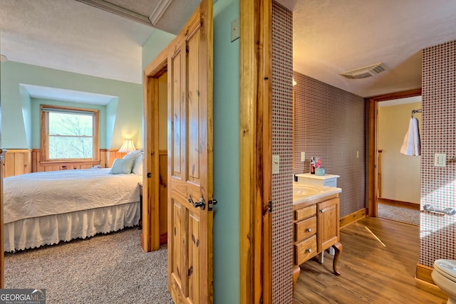 bedroom featuring wooden walls, light wood-type flooring, and a textured ceiling