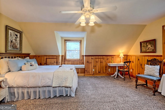 bedroom with wood walls, vaulted ceiling, carpet flooring, and ceiling fan