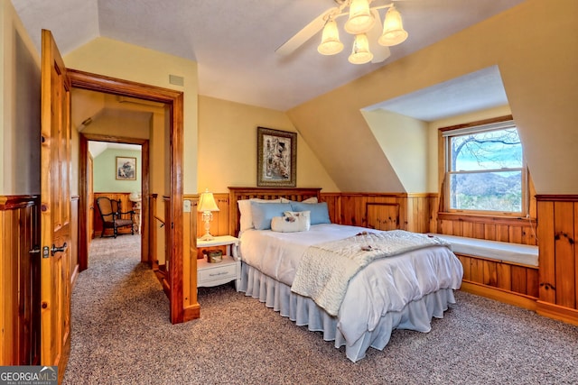 bedroom with carpet floors, wooden walls, lofted ceiling, and ceiling fan