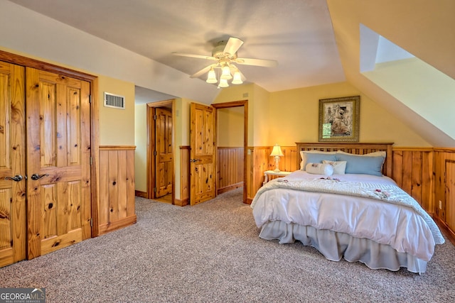 bedroom with lofted ceiling, wooden walls, ceiling fan, and carpet