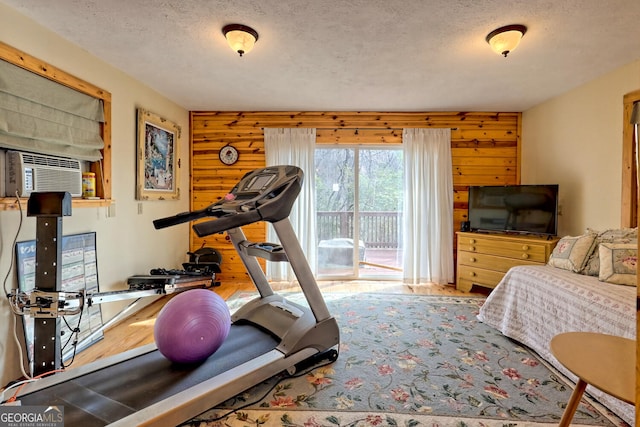 workout area featuring wood walls, cooling unit, and a textured ceiling