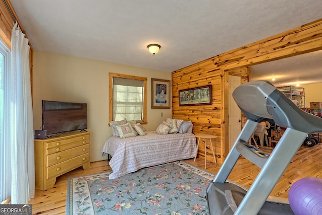 bedroom with wooden walls and light hardwood / wood-style floors