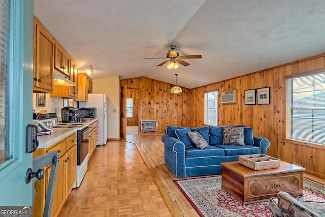 living room featuring ceiling fan, lofted ceiling, wood walls, and a wealth of natural light