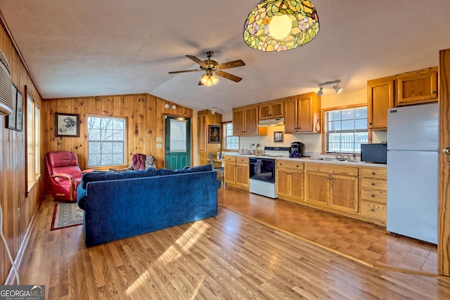 kitchen featuring lofted ceiling, wooden walls, white appliances, and light hardwood / wood-style flooring