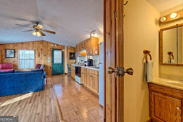 kitchen featuring ceiling fan, lofted ceiling, wood walls, light parquet flooring, and electric range