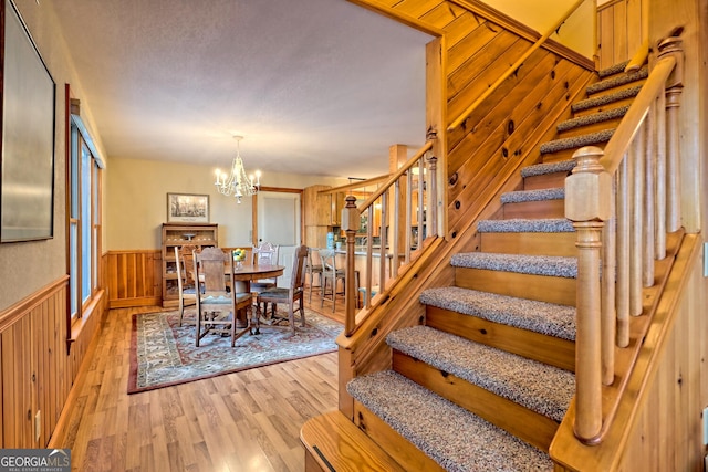 dining room featuring wooden walls, a chandelier, and light hardwood / wood-style floors