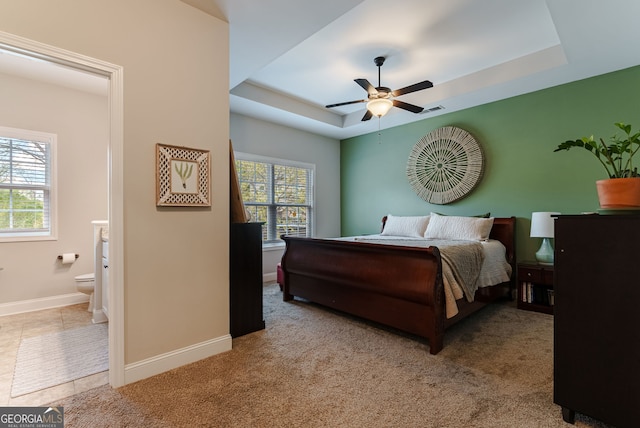 tiled bedroom featuring ceiling fan, multiple windows, and a raised ceiling