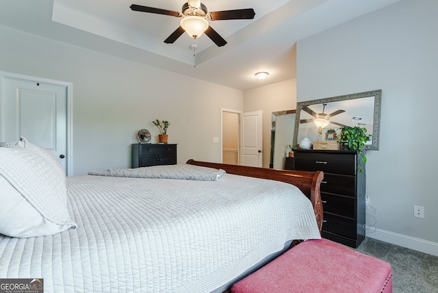 bedroom with carpet flooring, ceiling fan, and a tray ceiling