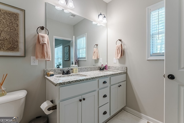 bathroom featuring toilet and double vanity