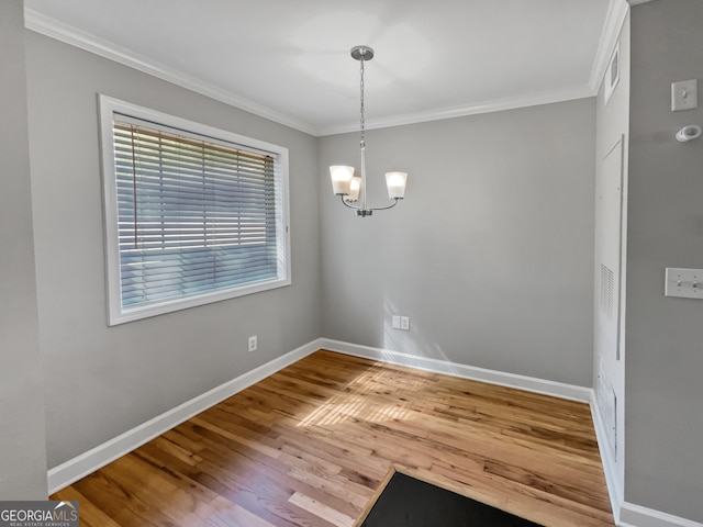 empty room with light hardwood / wood-style flooring, crown molding, and a chandelier