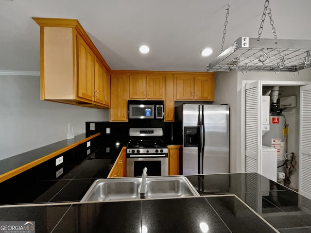 kitchen with washer / dryer, tile counters, stainless steel appliances, gas water heater, and sink