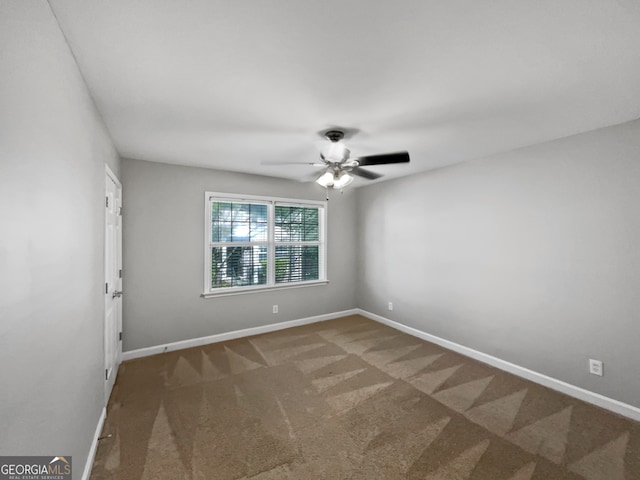 spare room featuring ceiling fan and dark colored carpet