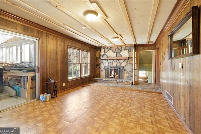 unfurnished living room featuring light parquet flooring, a fireplace, and wood walls