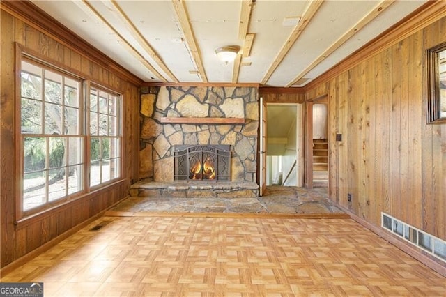 unfurnished living room with a stone fireplace, light parquet flooring, and wood walls