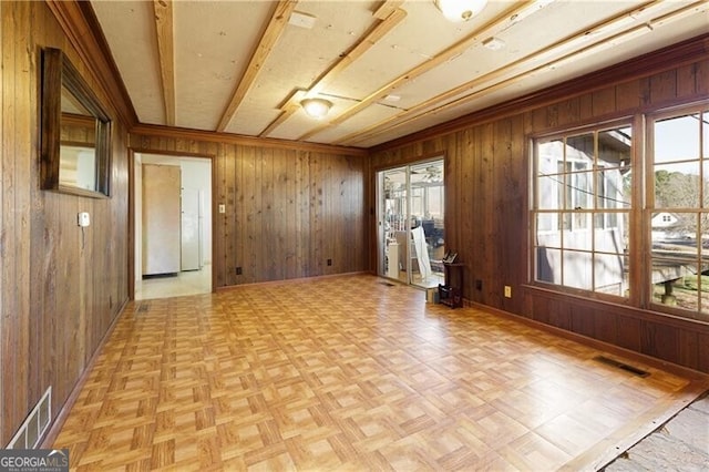 spare room featuring light parquet flooring, a wealth of natural light, and wooden walls