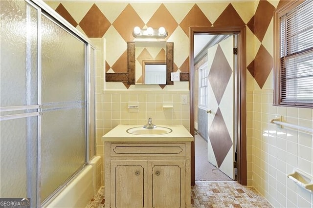 bathroom with enclosed tub / shower combo, vanity, and tile walls