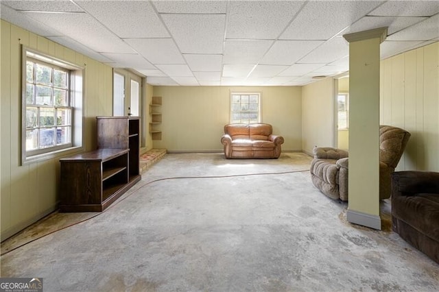 living room featuring a paneled ceiling and wooden walls