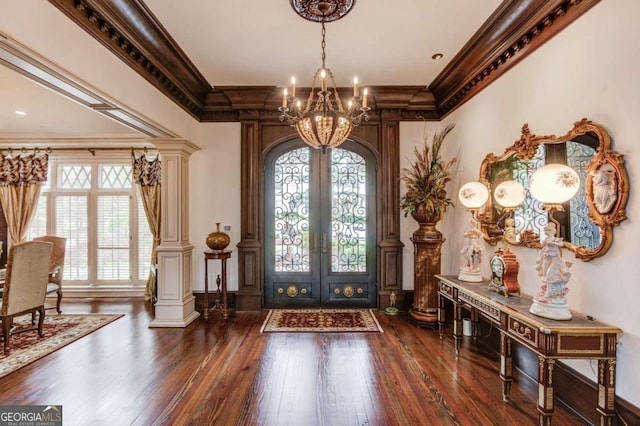 entrance foyer featuring dark hardwood / wood-style floors, a notable chandelier, and ornamental molding