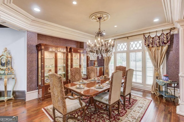 dining room featuring a notable chandelier, dark wood-type flooring, decorative columns, and ornamental molding