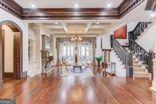 foyer entrance featuring wood-type flooring, beam ceiling, coffered ceiling, a chandelier, and crown molding