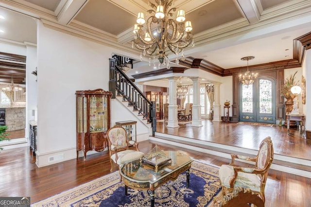 living room featuring dark hardwood / wood-style floors, decorative columns, a notable chandelier, crown molding, and french doors