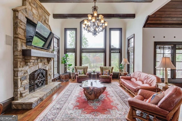 living room with beamed ceiling, a fireplace, a chandelier, a towering ceiling, and hardwood / wood-style flooring