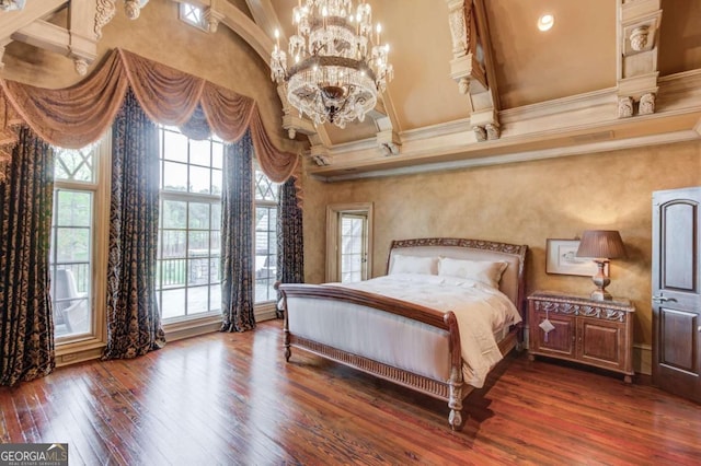 bedroom featuring an inviting chandelier, ornamental molding, a high ceiling, and dark hardwood / wood-style flooring