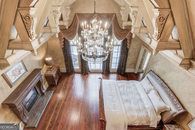 foyer entrance with ornate columns, dark hardwood / wood-style flooring, a towering ceiling, and an inviting chandelier