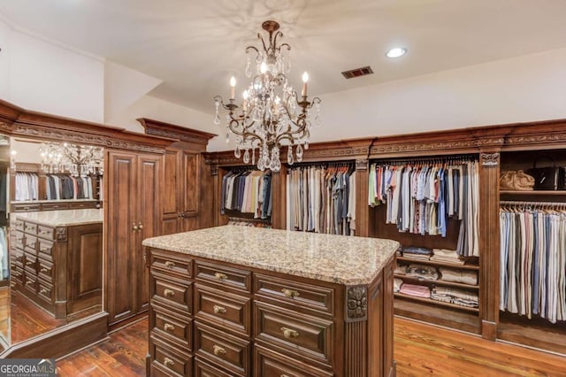 walk in closet with a notable chandelier and dark wood-type flooring