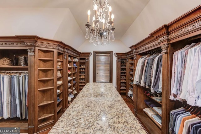 walk in closet with an inviting chandelier, dark hardwood / wood-style floors, and vaulted ceiling