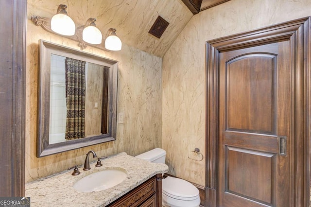 bathroom featuring lofted ceiling, toilet, and vanity