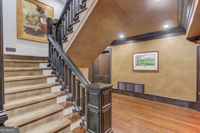 stairway with dark hardwood / wood-style flooring and ornamental molding