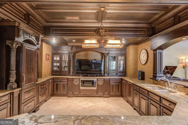 kitchen featuring pendant lighting, stainless steel microwave, light tile floors, sink, and light stone countertops