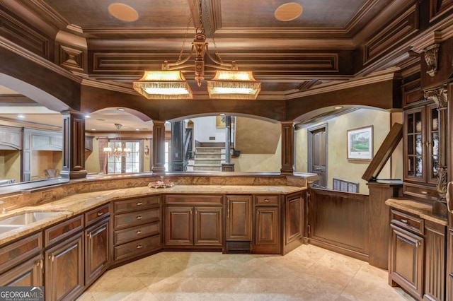 kitchen with decorative light fixtures, light stone countertops, light tile floors, and ornate columns