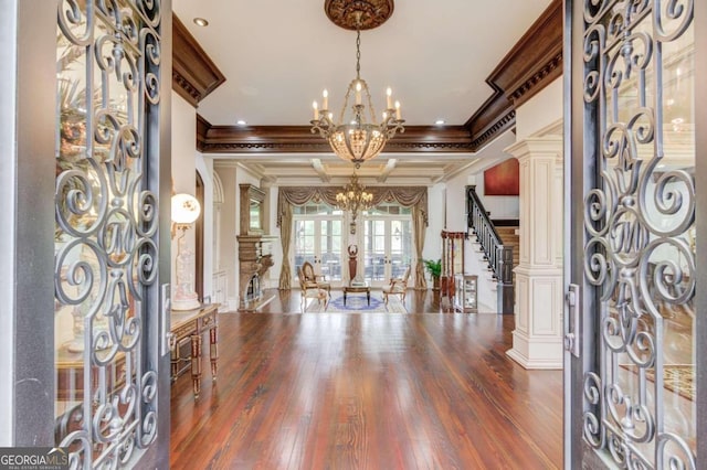 foyer with coffered ceiling, dark wood-type flooring, beamed ceiling, a notable chandelier, and ornamental molding