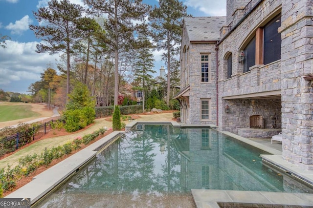 view of pool with an outdoor stone fireplace