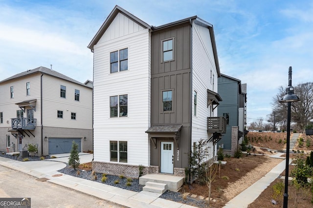 view of front of home featuring a garage, concrete driveway, brick siding, and board and batten siding