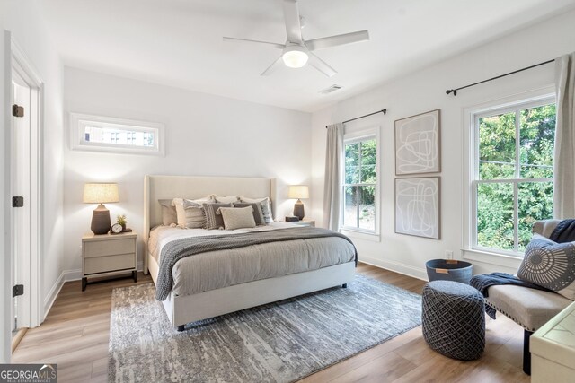 bedroom with ceiling fan, multiple windows, and hardwood / wood-style floors