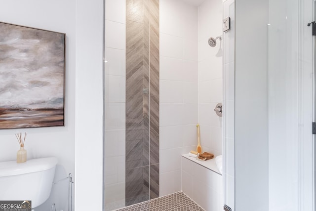 bathroom featuring a tile shower and toilet