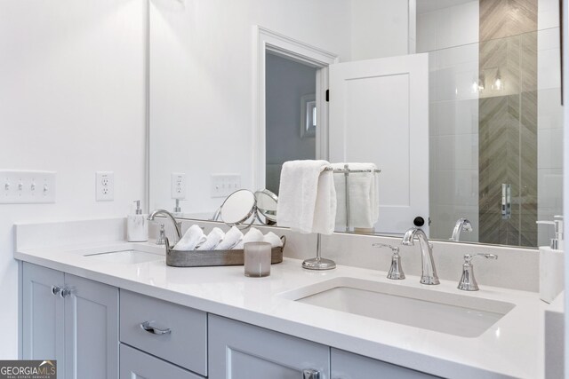 bathroom with dual sinks, vanity with extensive cabinet space, and an enclosed shower