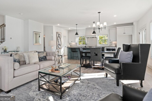 living room featuring sink, an inviting chandelier, and hardwood / wood-style flooring