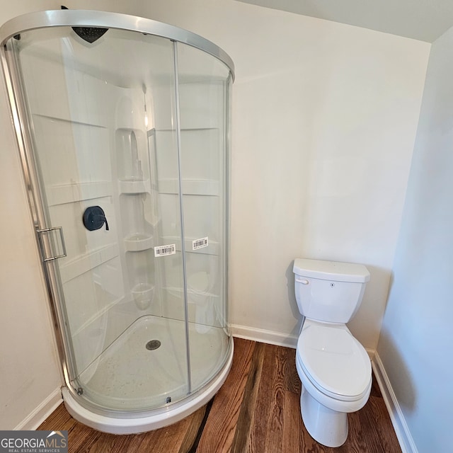 bathroom featuring walk in shower, toilet, and hardwood / wood-style floors