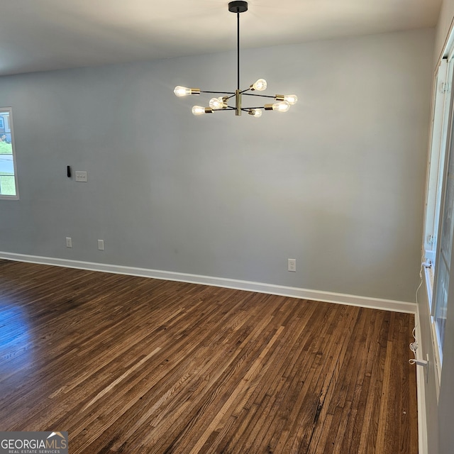 unfurnished room with a chandelier and dark hardwood / wood-style floors