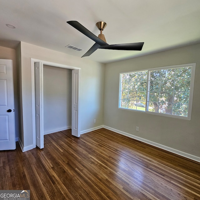 unfurnished bedroom with a closet, dark hardwood / wood-style floors, and ceiling fan