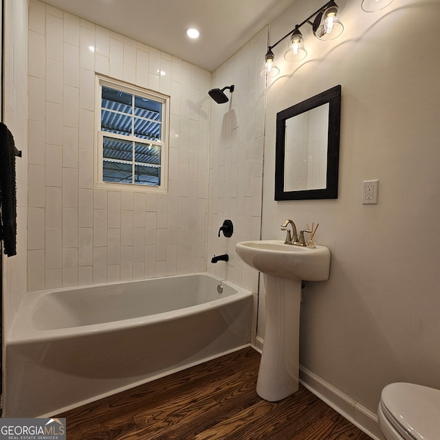 bathroom featuring tiled shower / bath, toilet, and wood-type flooring