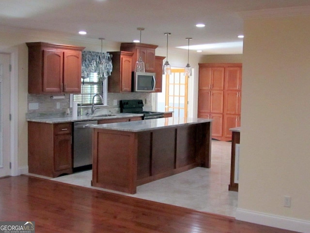 kitchen featuring a kitchen island, appliances with stainless steel finishes, backsplash, hanging light fixtures, and sink